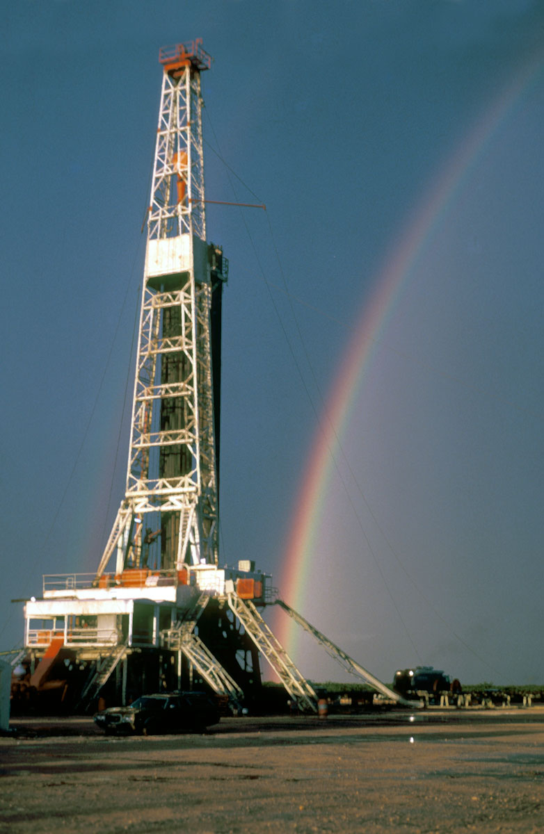 An image of an oil rig with a rainbow behind it.
